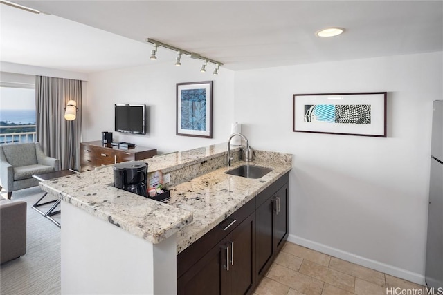 1777 Ala Moana Blvd Unit 2206, Honolulu, HI 96815 - kitchen featuring sink, light stone counters, dark brown cabinets, track lighting, and kitchen peninsula