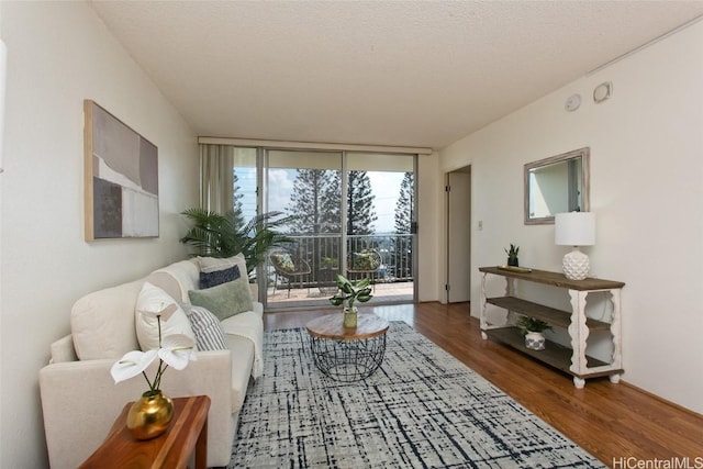 living room featuring a textured ceiling, a wall of windows, and wood finished floors