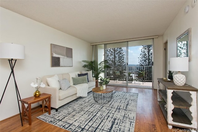 living room with a textured ceiling, floor to ceiling windows, and wood finished floors