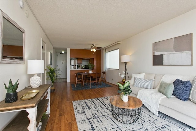 living room with ceiling fan, a textured ceiling, and wood finished floors