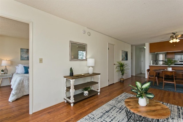 living area featuring ceiling fan, a textured ceiling, and wood finished floors