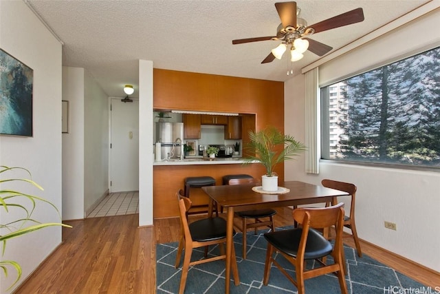 dining space featuring a ceiling fan, a textured ceiling, and wood finished floors