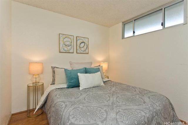 bedroom with a textured ceiling and wood finished floors