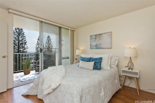 bedroom with access to exterior, a textured ceiling, floor to ceiling windows, and wood finished floors