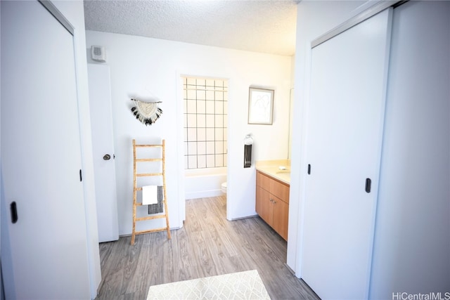 full bathroom with bathing tub / shower combination, vanity, wood-type flooring, a textured ceiling, and toilet