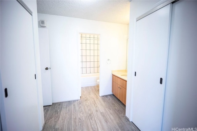 full bathroom with shower / washtub combination, wood-type flooring, vanity, toilet, and a textured ceiling