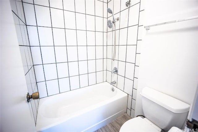 bathroom featuring tiled shower / bath combo, hardwood / wood-style flooring, and toilet