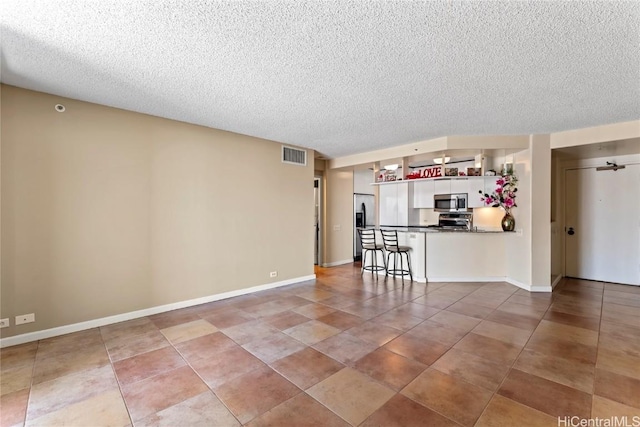 unfurnished living room with ceiling fan, tile patterned floors, and a textured ceiling