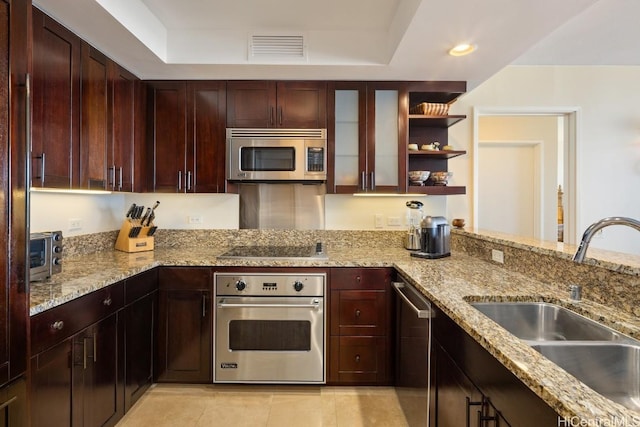 kitchen with light stone counters, sink, stainless steel appliances, and a raised ceiling