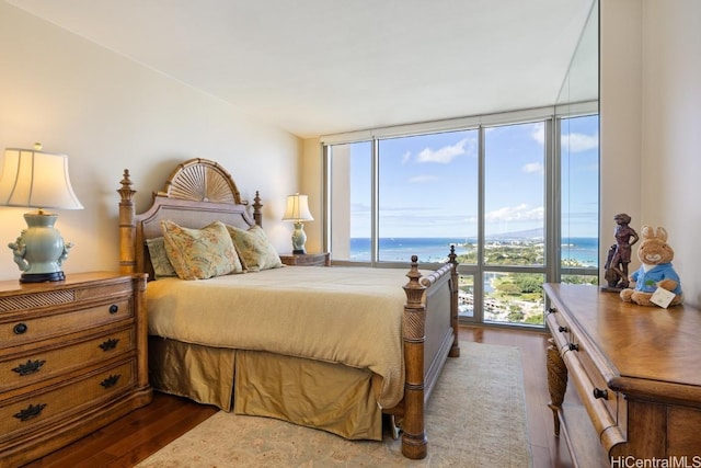 bedroom with hardwood / wood-style floors, a wall of windows, and a water view