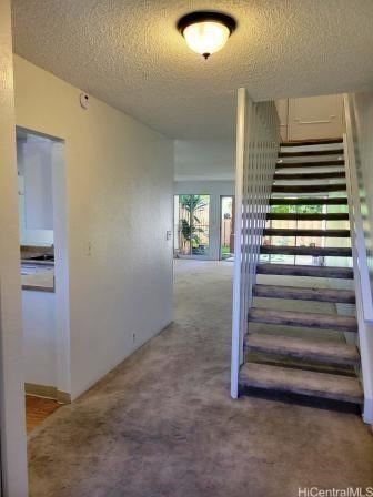 staircase featuring carpet floors and a textured ceiling