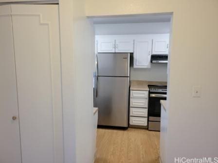 kitchen featuring appliances with stainless steel finishes, range hood, light hardwood / wood-style flooring, and white cabinets