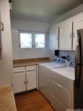 clothes washing area featuring cabinets, dark hardwood / wood-style flooring, and independent washer and dryer