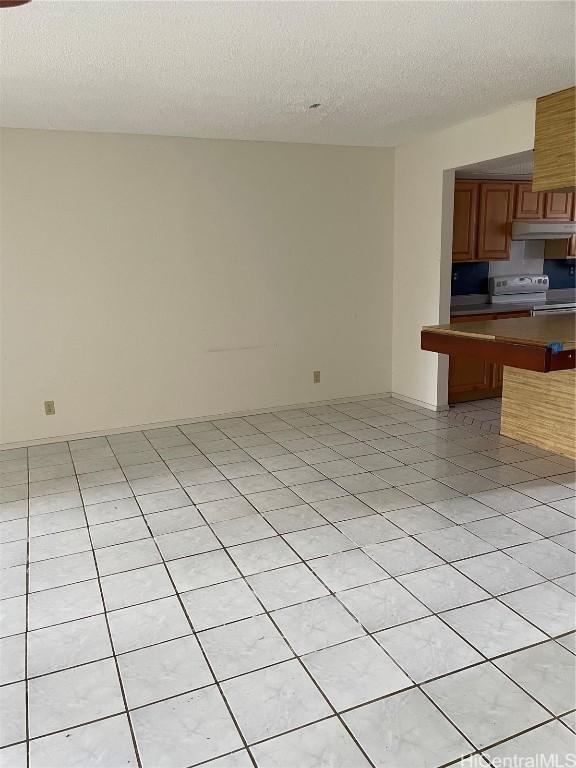 kitchen with light tile patterned floors, a breakfast bar, white range with electric stovetop, a textured ceiling, and kitchen peninsula