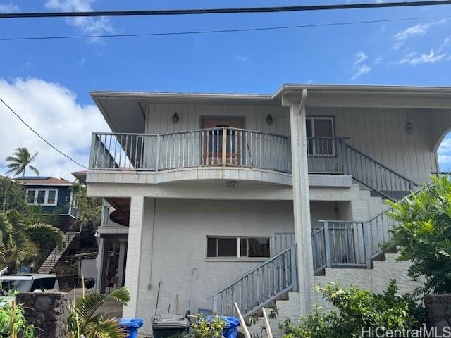 back of property featuring a balcony and stairway