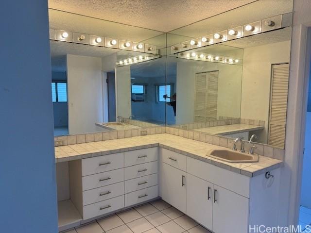 bathroom with a textured ceiling, vanity, a closet, and tile patterned floors