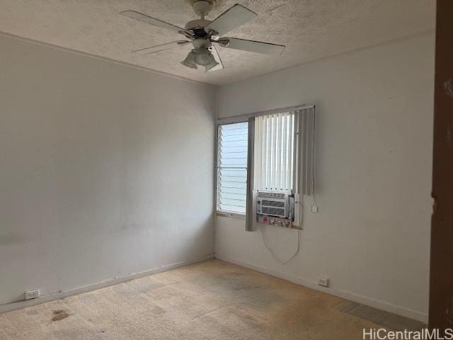 spare room featuring a textured ceiling, cooling unit, light colored carpet, a ceiling fan, and baseboards