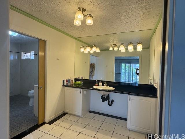 bathroom featuring toilet, tile patterned flooring, a textured ceiling, and a sink