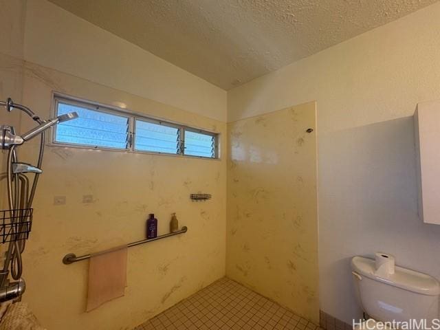 bathroom featuring a textured ceiling, tiled shower, toilet, and a healthy amount of sunlight