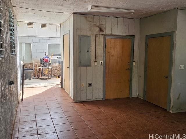 interior space with concrete block wall, electric panel, and a textured ceiling