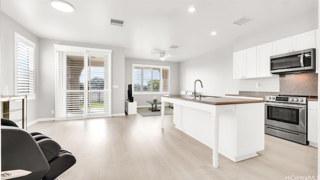 kitchen featuring sink, a center island with sink, appliances with stainless steel finishes, a kitchen breakfast bar, and white cabinets