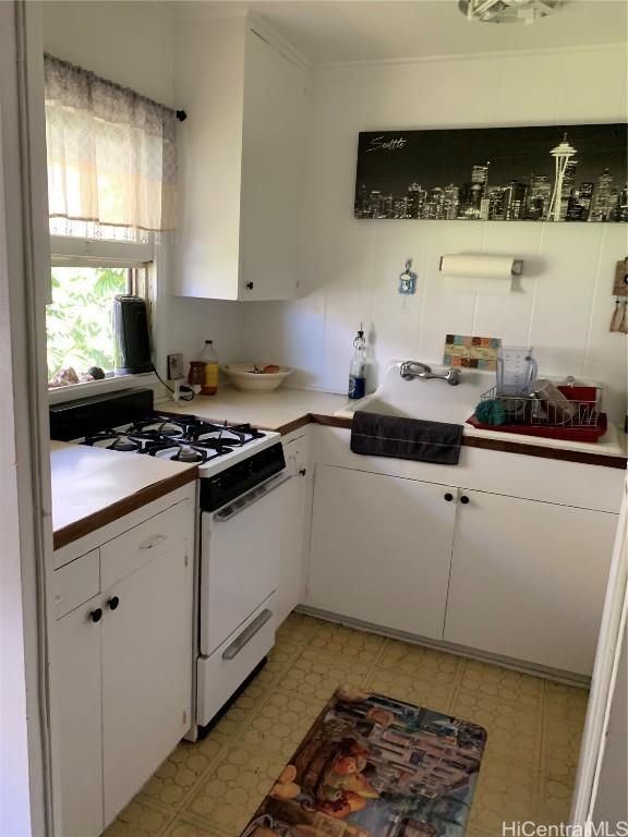 kitchen featuring crown molding, sink, white gas range oven, and white cabinets