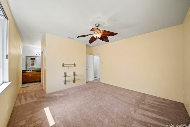 unfurnished bedroom featuring visible vents, ceiling fan, light carpet, and ensuite bathroom