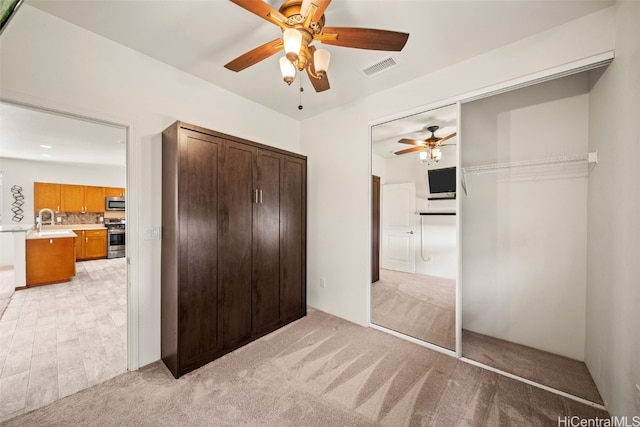 unfurnished bedroom featuring light carpet, ceiling fan, visible vents, and a closet