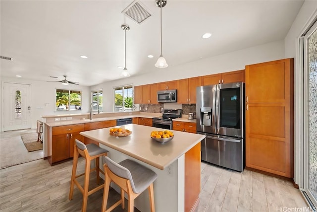 kitchen with visible vents, brown cabinets, a peninsula, stainless steel appliances, and light countertops