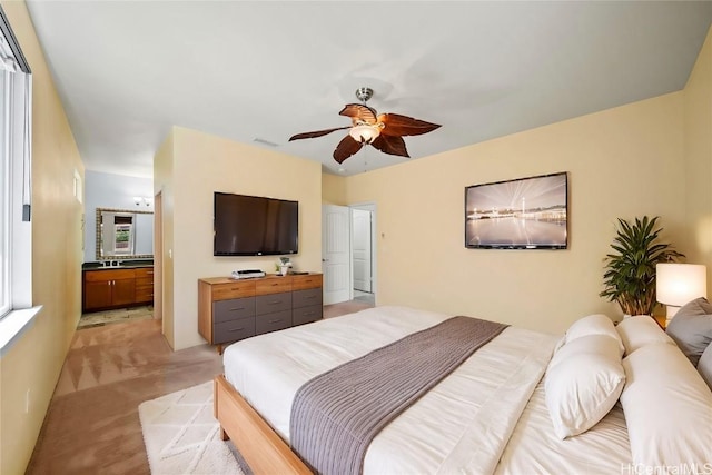 bedroom featuring light carpet, a ceiling fan, visible vents, and connected bathroom