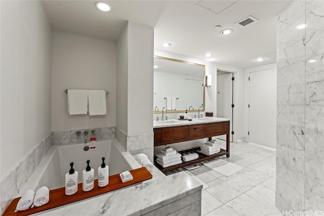 bathroom with vanity, tile walls, and a bathtub