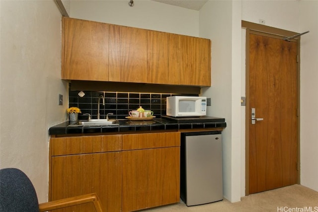 kitchen with tasteful backsplash, light colored carpet, sink, and stainless steel refrigerator