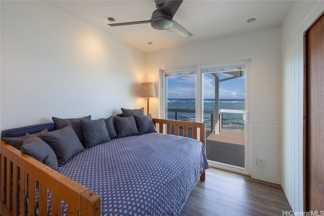 bedroom with a water view, dark wood finished floors, and ceiling fan