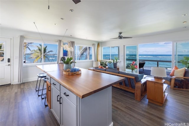 kitchen with white cabinets, a ceiling fan, open floor plan, a center island, and a water view