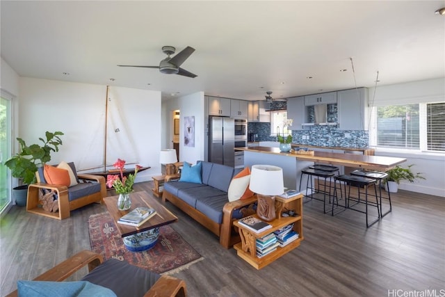 living area with ceiling fan, dark wood-style flooring, and baseboards