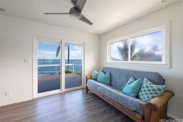 sitting room featuring a water view, ceiling fan, and dark wood-type flooring