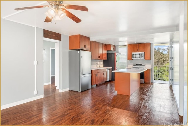 kitchen with brown cabinetry, dark wood finished floors, a center island, stainless steel appliances, and light countertops