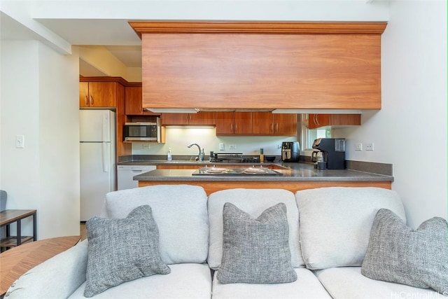 kitchen featuring open floor plan, white appliances, dark countertops, and a sink