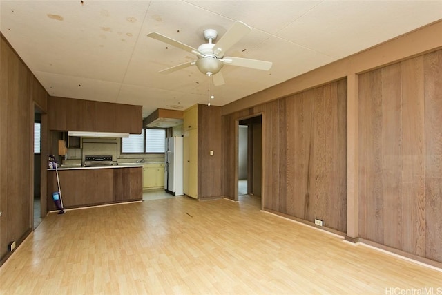 kitchen with stove, light hardwood / wood-style flooring, wood walls, and white fridge