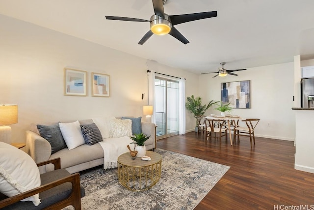 living area with dark wood-type flooring, a ceiling fan, and baseboards