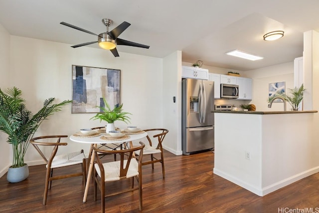 kitchen featuring dark wood-style floors, dark countertops, appliances with stainless steel finishes, white cabinets, and baseboards