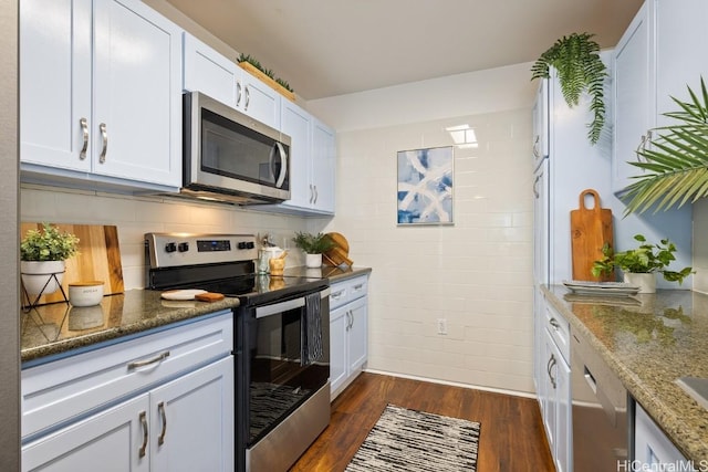 kitchen featuring stainless steel appliances, dark stone counters, dark wood-style flooring, and white cabinetry