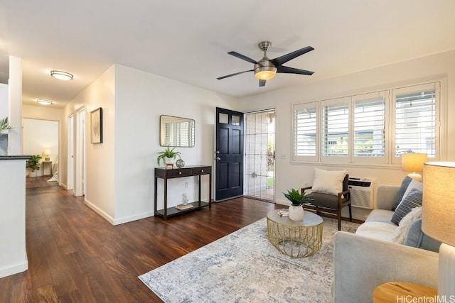 living area featuring a ceiling fan, dark wood finished floors, and baseboards