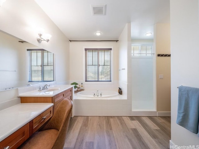 bathroom with vanity, tiled tub, and wood-type flooring