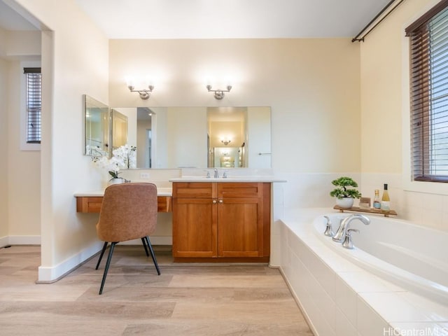 bathroom featuring vanity, wood-type flooring, and tiled tub