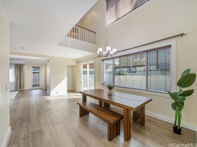 dining area featuring an inviting chandelier, light hardwood / wood-style flooring, and a high ceiling