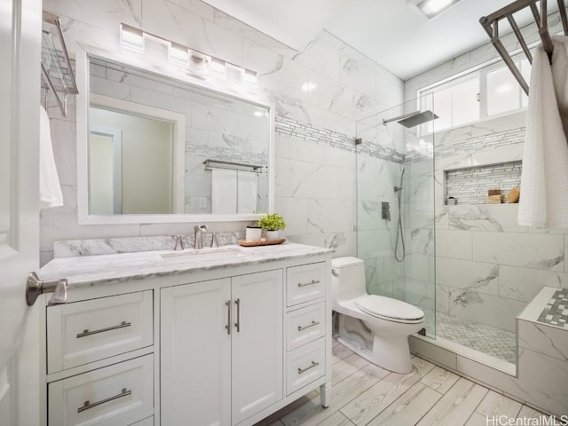 bathroom with vanity, tile walls, toilet, and tiled shower