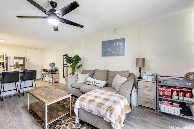 living room with ceiling fan, hardwood / wood-style flooring, and a textured ceiling