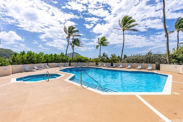 view of swimming pool featuring a hot tub, a mountain view, and a patio area