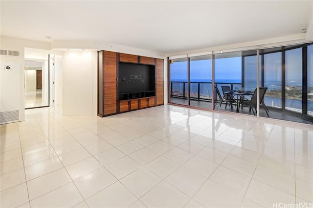 unfurnished living room with a wall of windows, light tile patterned flooring, and visible vents